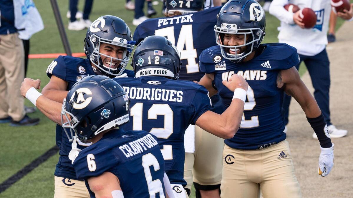 UC Davis’ Hunter Rodrigues (12) is congratulated by teammates Lance Babb II, left, and Jared Harrell after scoring against Cal Poly during the second quarter of the Aggies’ first home football game of the spring season Saturday in Davis. Saturday marked the 1,000th football game in the storied history of the UC Davis Aggies.