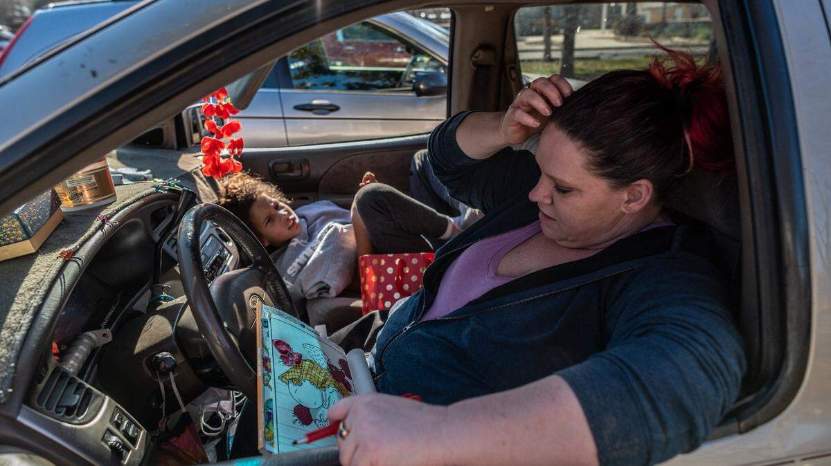 Kristi Phillimps, 47, says she likes to color to distract her from all the stress of being homeless with her son Tyree Franklin, 11, at left, when they arrived at South Natomas Community Park to camp overnight because they could not afford to pay for another night in a hotel on Saturday, Jan.17, 2021.