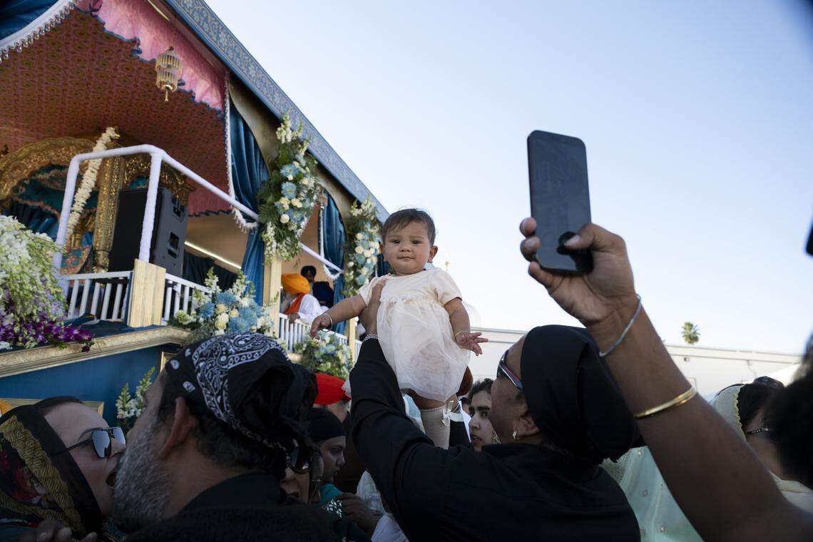 A baby is lifted in front of the main float of Nagar Kirtan, also known as the Sikh Parade, in Sutter County on Sunday, Nov. 2, 2025.
