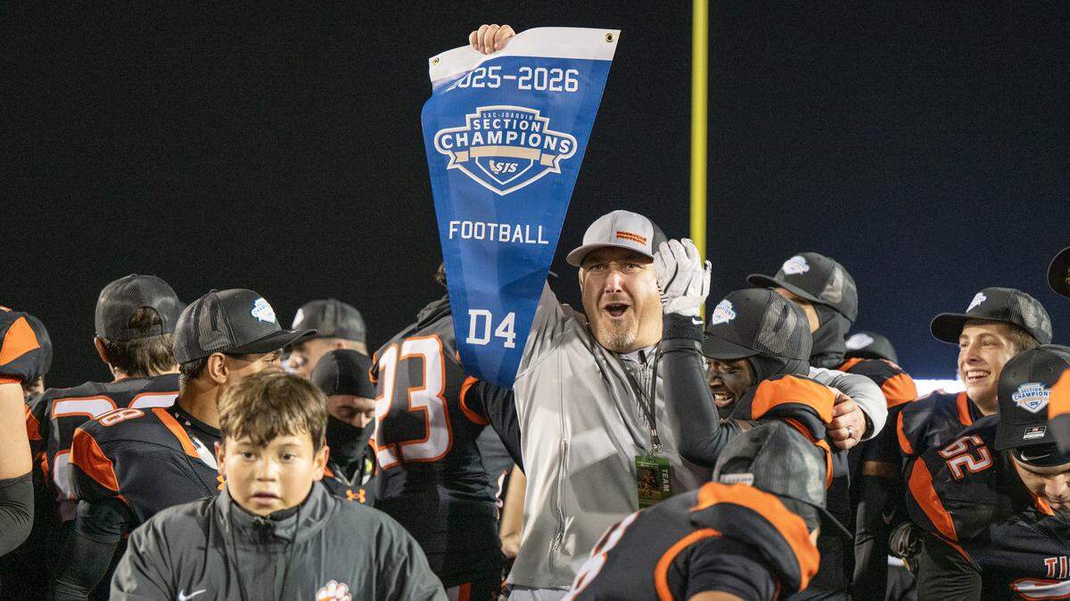 Roseville Tigers coach Adam Reinking holds up the section banner following the 31-29 victory over the East Union Lancers the CIF Sac-Joaquin Section football Division lV championship on Saturday at Hughes Stadium in Sacramento.