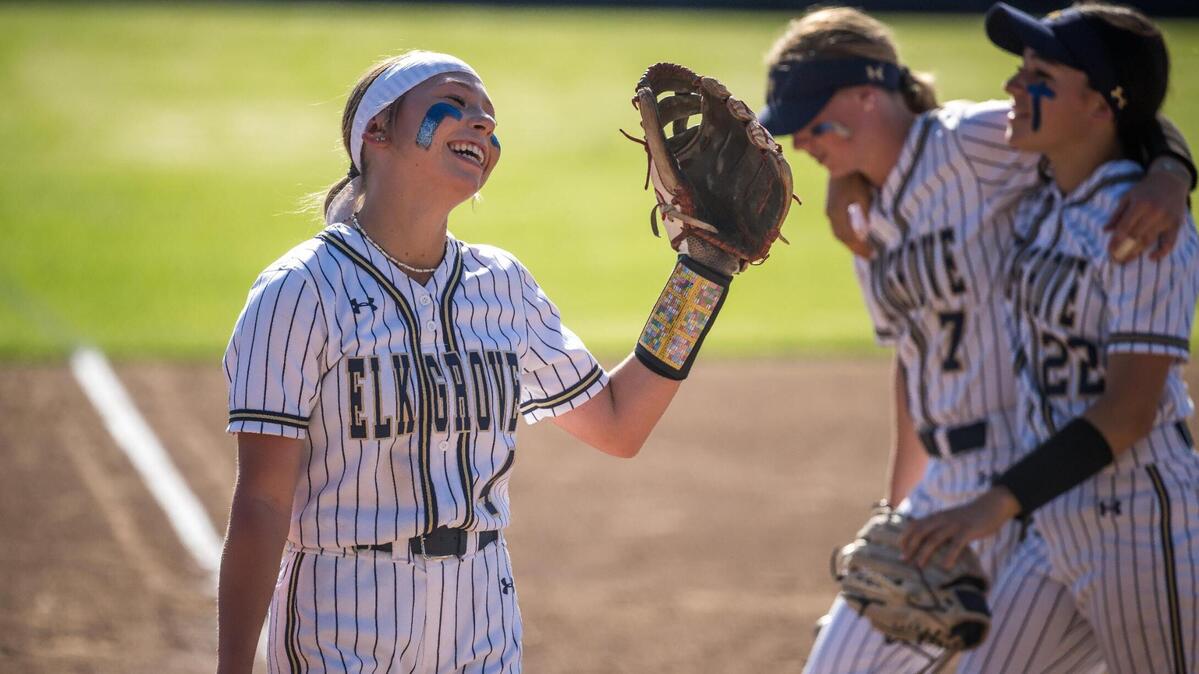 Elk Grove Thundering Herd winning pitcher Madison Carda (4) smiles as teammates Gabby Sotelo (22), right, and Loie Moore (7) walk by after ending the Rodriguez (Fairfield) fifth inning at-bat in the high school girls softball CIF Sac-Joaquin Section Division II first round playoff game Tuesday, May 16, 2023, at Elk Grove High School. The Thundering Herd beat the Mustangs 8-1 to advance to the quarterfinals.