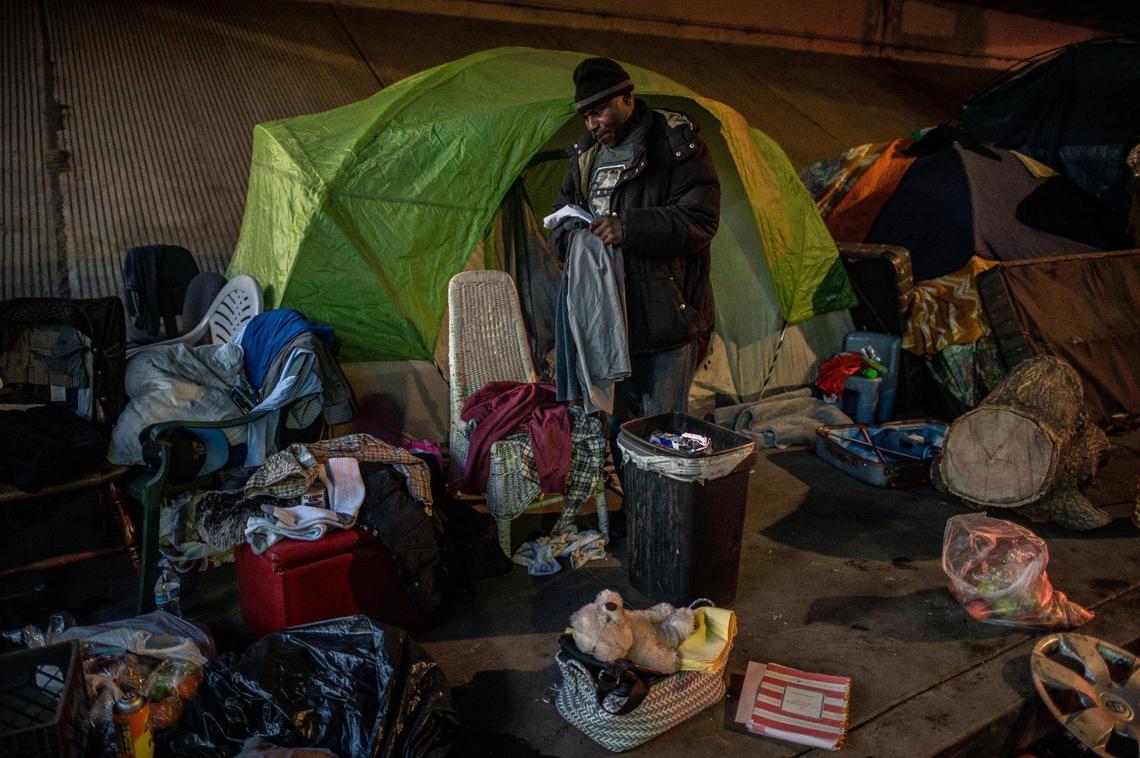 Harold Carter, 52, sorts through the tent that belonged to his partner of 27 years, Karen Hunter, 57, on Friday. Hunter died on Tuesday night during a severe storm, at a homeless encampment on 26th Street under the W-X freeway in Sacramento. “I’m going to have to donate most of her clothes. I hate that,” he said. Her teddy bear and scheduling appointment book are seen in the foreground.