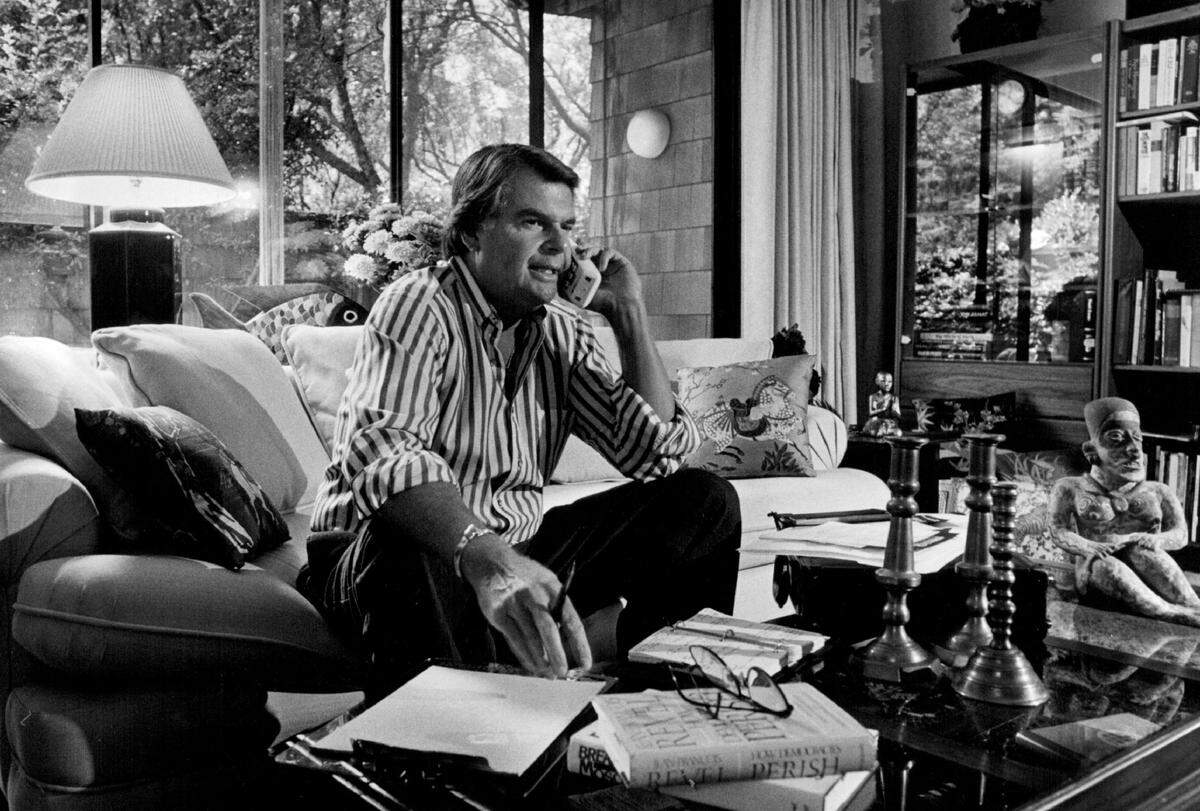 KCRA anchor Stan Atkinson speaks on the phone at home in 1986, surrounded by memorabilia of his career and wide-ranging travels.