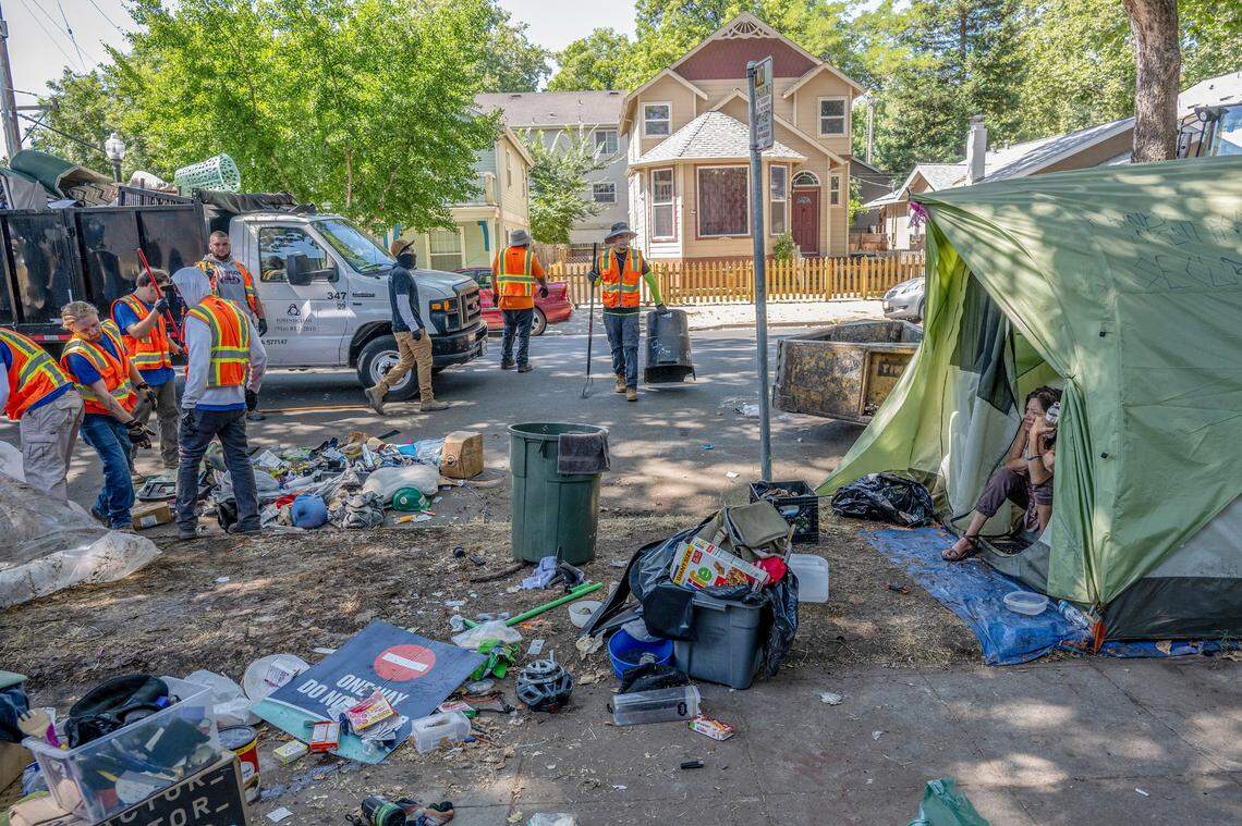Alicia Peterson, 55, watches as contract workers for the city of Sacramento discard the belongings of neighboring campers during a homeless sweep on C Street in Sacramento on July 19.