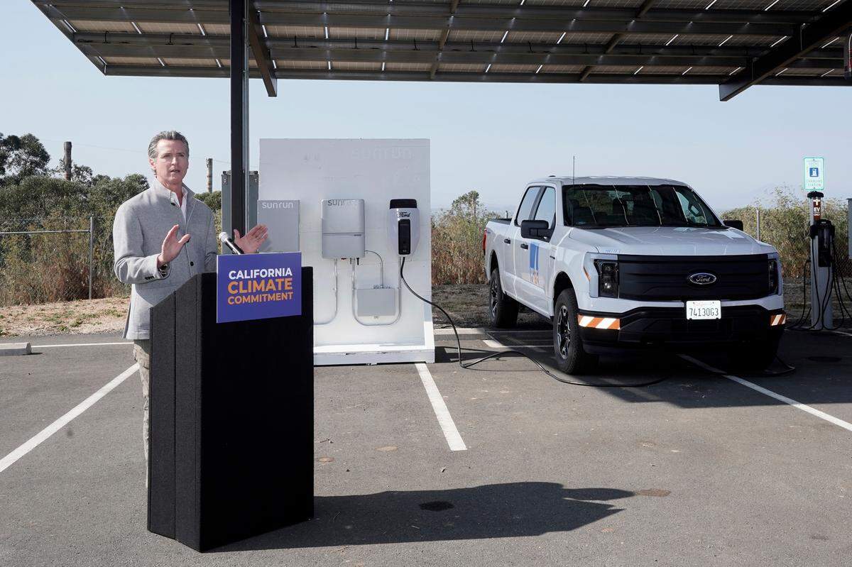 With a solar panels above him and a charging station display in the background, Gov. Gavin Newsom discusses climate legislation he is about to sign at Mare Island in Vallejo in September. Newsom signed a package of legislation that accelerates the climate goals of the nation’s most populous state.