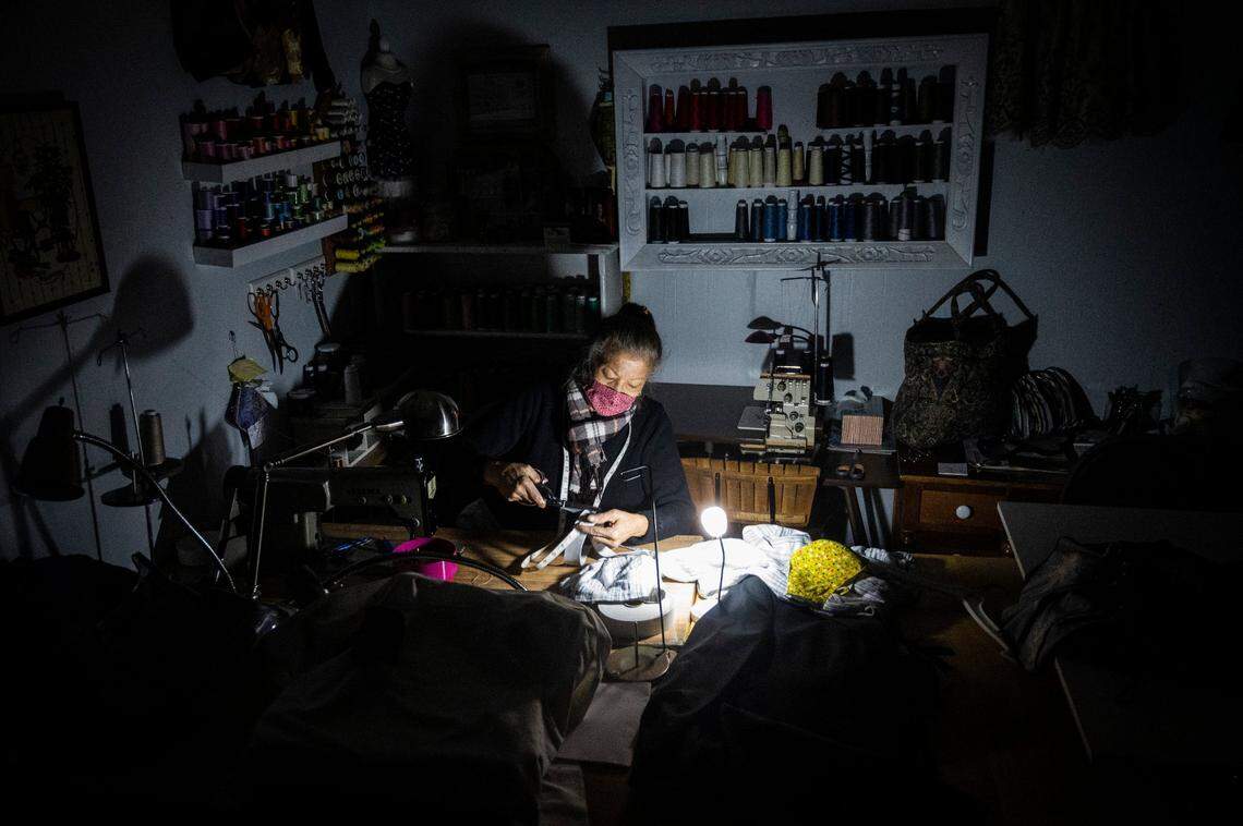 Rose Turner of Rose Alteration cuts elastic as a battery powered light illuminates her work during a power outage in her shop in downtown Placerville in 2020. PG&E shut off power to 355,000 homes and businesses as part of a public safety power shutoff that started Sunday night because of a severe windstorm.