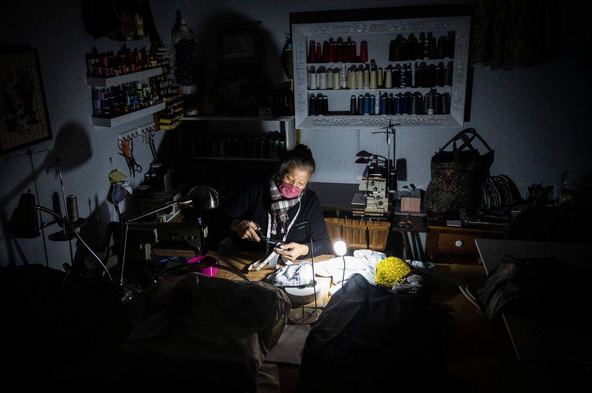 Rose Turner of Rose Alteration cuts elastic as a battery powered light illuminates her work during a power outage in her shop in downtown Placerville in 2020. PG&E shut off power to 355,000 homes and businesses as part of a public safety power shutoff that started Sunday night because of a severe windstorm.