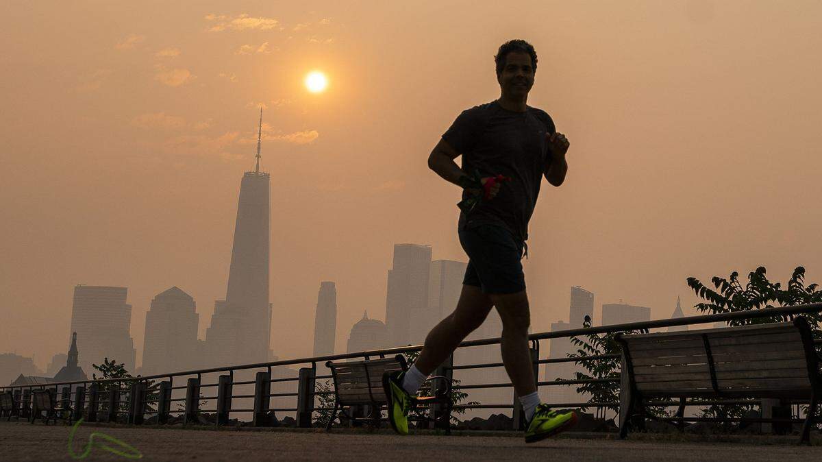 The One World Trade Center and the New York skyline is seen in the background as a man jogs through the Liberty State Park while the smoke from Canada wildfires covers the Manhattan borough on Thursday, June 8.