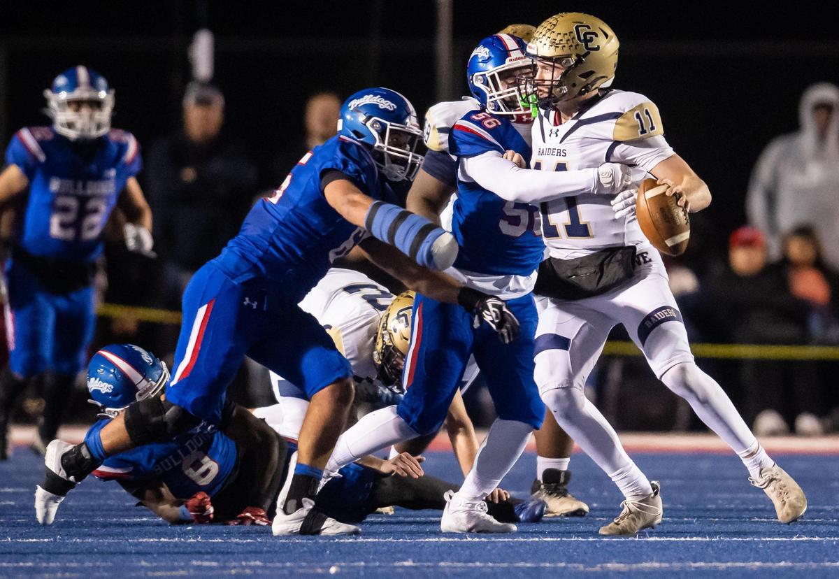 Central Catholic Raider quarterback Tyler Wentworth (11) is sacked by Folsom Bulldog tackle Lucas Hardeman (56), center, and tackle Elijah Gulewich (65) during the second quarter of the CIF Sac-Joaquin Section high school football playoff game Friday, Nov. 18, 2022, at Folsom High School.