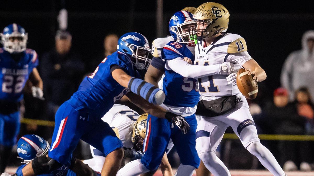 Central Catholic Raider quarterback Tyler Wentworth (11) is sacked by Folsom Bulldog tackle Lucas Hardeman (56), center, and tackle Elijah Gulewich (65) during the second quarter of the CIF Sac-Joaquin Section high school football playoff game Friday, Nov. 18, 2022, at Folsom High School.