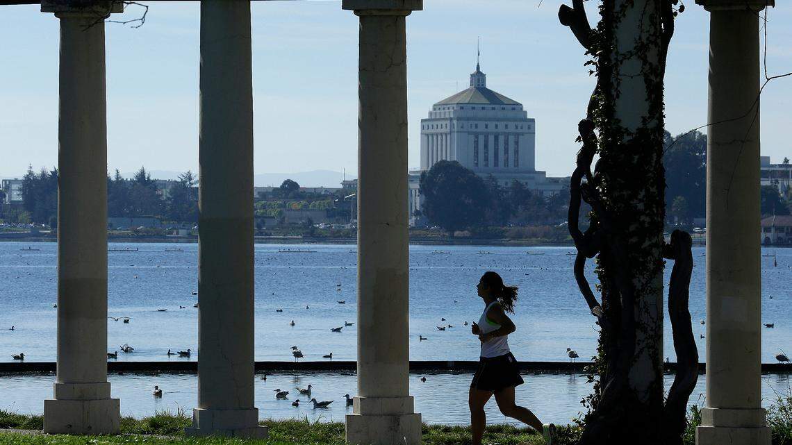 A woman jogs around Lake Merritt in 2016.  Online videos of a  jogger tearing apart a homeless man’s camp Friday beside the Oakland, Calif., lake - including tossing some of the man’s blankets and clothes into the water - have sparked an outcry.