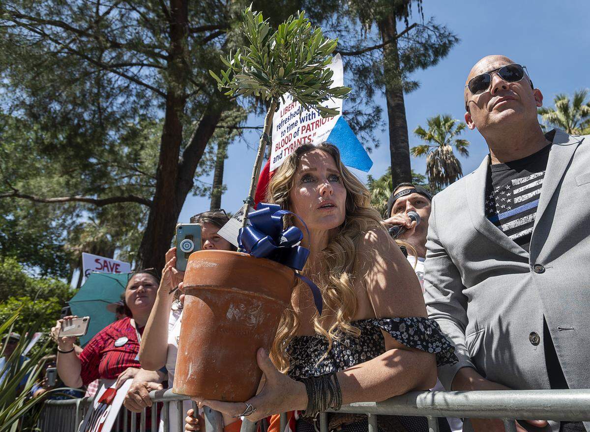 Tara Thornton of the Freedom Angels holds an olive tree for law enforcement officers with Pastor Tim Thompson during a protest at the State Capital on Thursday, May 7, 2020 in Sacramento during the coronavirus pandemic.