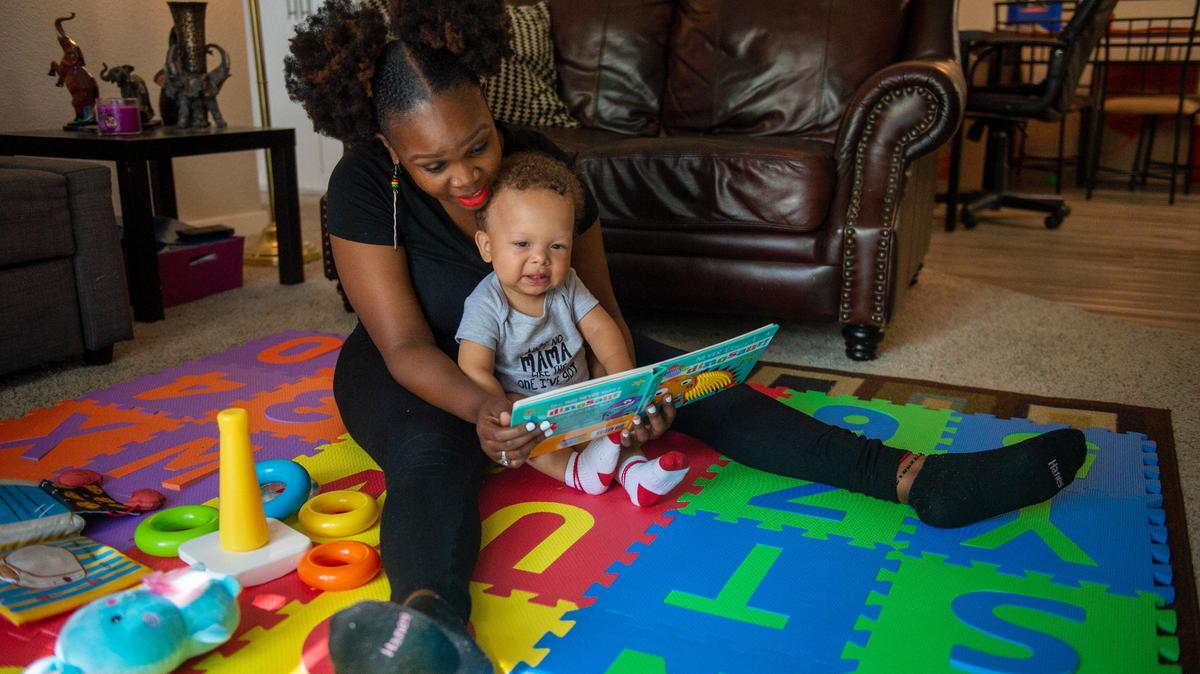 Racquel Payton, 30, reads to her son, Yahir, 1, in her living room, Tuesday, Aug. 20, 2019 in Sacramento. The preschool teacher and single mom says she struggles to pay for his daycare. She said both her parents have died. “I was my mother’s only child so it’s been really hard,” said Payton who has little family support here in Sacramento.
