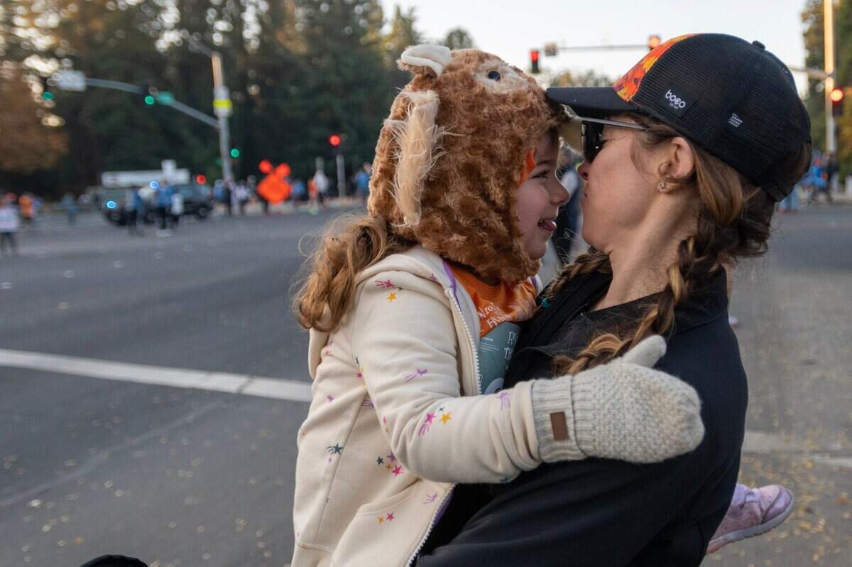 Marcela Estrada hugs her daughter, Francesca Norman, 4, wearing a turkey hat before the start of the Run to Feed the Hungry in Sacramento on Thursday.