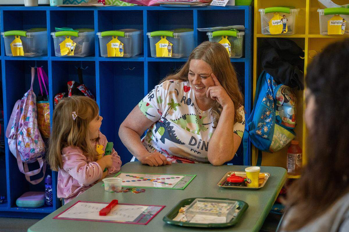 Teacher Amanda Chapman listens to Raelyn, 3, after she places magnets to form the letter X during a preschool lesson at Edward Kelley parent participation preschool in Rosemont on Thursday.