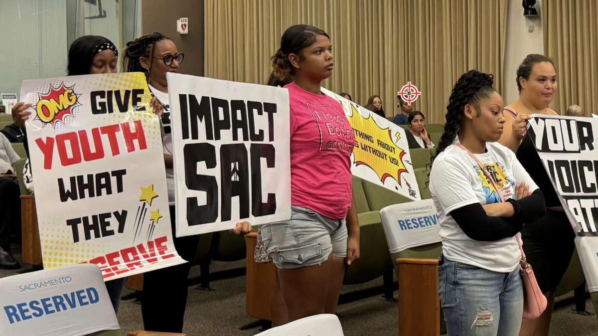 Youth and their advocates hold up signs as they await a chance to speak to the city council about Measure L on Tuesday, Sept. 24, 2024. The first grants were awarded in July. 