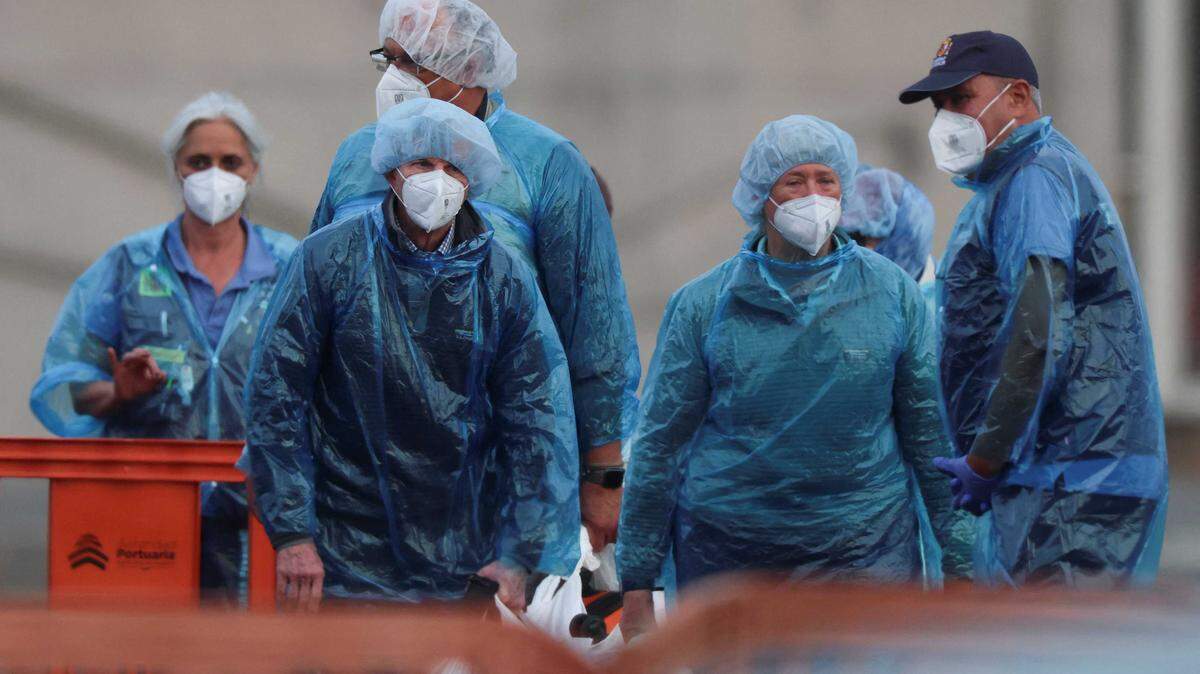 U.S. passengers from the cruise ship MV Hondius, affected by a hantavirus outbreak, stand on land Sunday after disembarking the ship, at the port of Granadilla de Abona, in Tenerife, Spain. Four California residents may have been exposed in the outbreak.