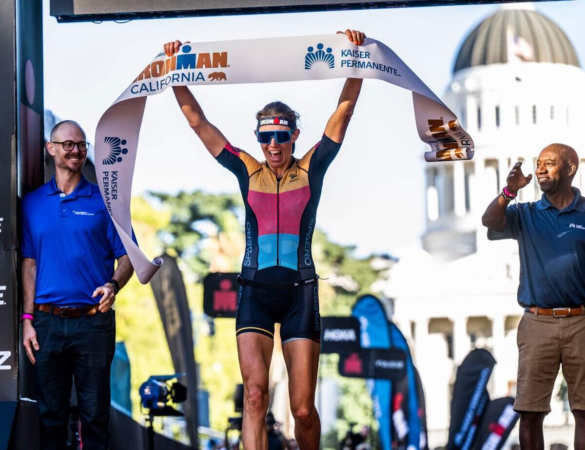 Liis Rametta of Park City, Utah, raises her arms after finishing in first place in the women’s category during the Ironman California triathlon in Sacramento on Sunday, Oct. 23, 2022.