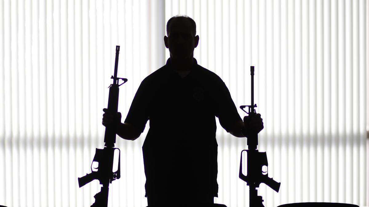 In this Aug. 29, 2017, photo, an ATF agent poses with homemade rifles, or “ghost guns,” at an ATF field office in Glendale, Calif. Police say Kevin Neal, who was barred from having guns because of a restraining order, made the two high-powered rifles he used in his shooting rampage in Northern California on Tuesday, Nov. 14. (AP Photo/Jae C. Hong)