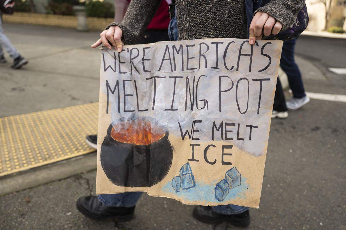 A march participant carries a sign that says "We're America's melting pot during a student-led protest against ICE at the state Capitol on Friday.