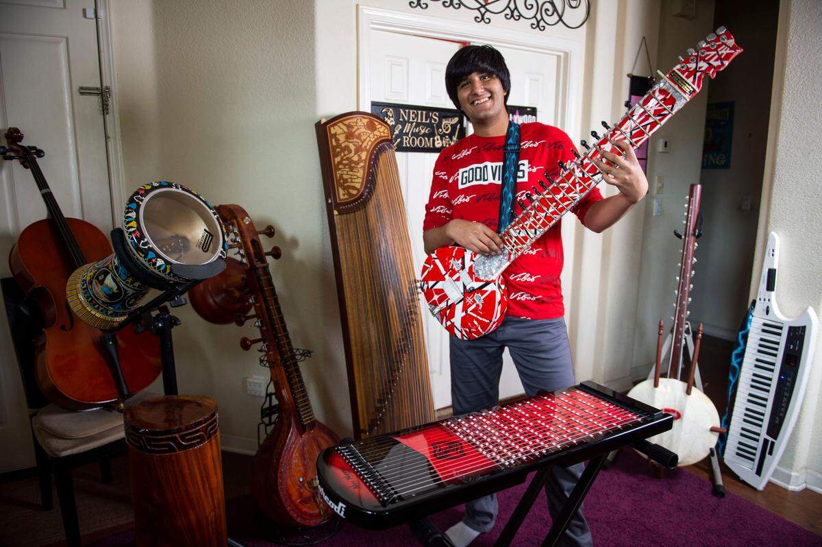 Neil Nayyar, 16, holds an Indian sitar while surrounded by some of his favorite instruments from around the world, at his home in Elk Grove on Friday, May 6, 2022. At 13, he won the world record as the youngest multi-instrumentalist and says he currently plays 114 musical instruments.