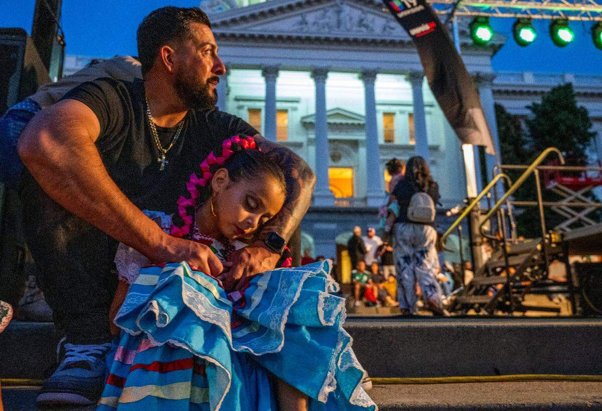 Sacramento resident Jose Jimenez holds his seven-year-old daughter Azul after she danced with her group Instituto Mazatlan Bellas Artes de Sacramento during the celebration of the Mexican Day of Independence on the west steps of the state Capitol on Thursday, Sept. 15, 2022.