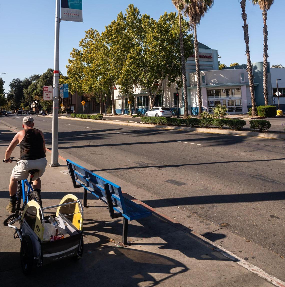 A man rides a bicycle with some belongings in tow earlier this month along Broadway across from the Walgreens. The drug store is the last remaining business in the small shopping center at the corner of Broadway and 15th Street where Jamba Juice and Starbucks have now closed.