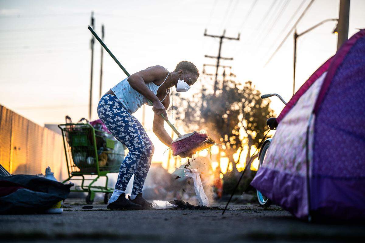 Natasha Howard sweeps trash where she camps Wednesday just outside the walls of a tiny homes village that was installed last summer by Sacramento County called the Safe Stay Community. “By June they said they would be open. We don’t have until June,” she said.