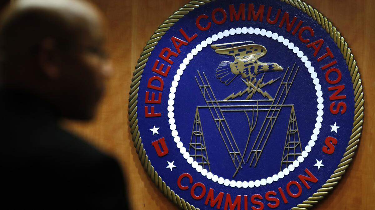 FILE - This Thursday, Dec. 14, 2017, photo, shows the seal of the Federal Communications Commission before a meeting in Washington. On Thursday, Dec. 21, 2017, the FCC proposed a $13.4 million fine on TV-station owner Sinclair for not identifying paid programming as advertising.