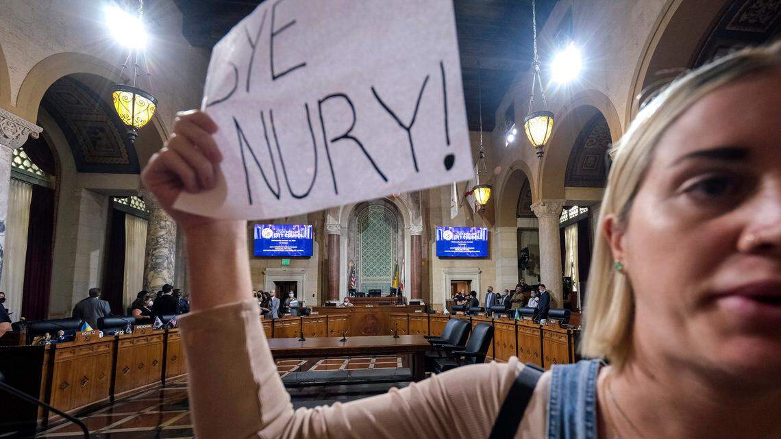 A woman holding a sign protest before cancellation of the Los Angeles City Council meeting Wednesday, Oct. 12, 2022, in Los Angeles.