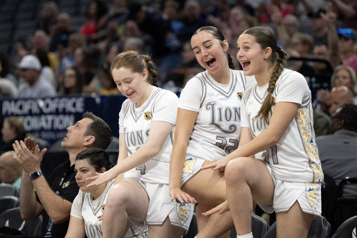 The Faith Christian Lions' Ella Haeberle (4), Esther Borlean (32), and Moriah Ely (31) strike a pose after a teammate’s made 3-pointer in the second half against the Palisades Dolphins in the CIF State Division IV girls basketball championship Saturday at Golden 1 Center.