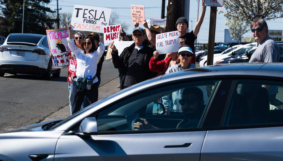 Demonstrators rally against Elon Musk as drivers depart the Tesla dealership on Arden Way near Sacramento on Saturday, March 8, 2025. More than 100 people lined both sides of street to protest the role of the tech billionaire and Tesla CEO in the Trump administration.