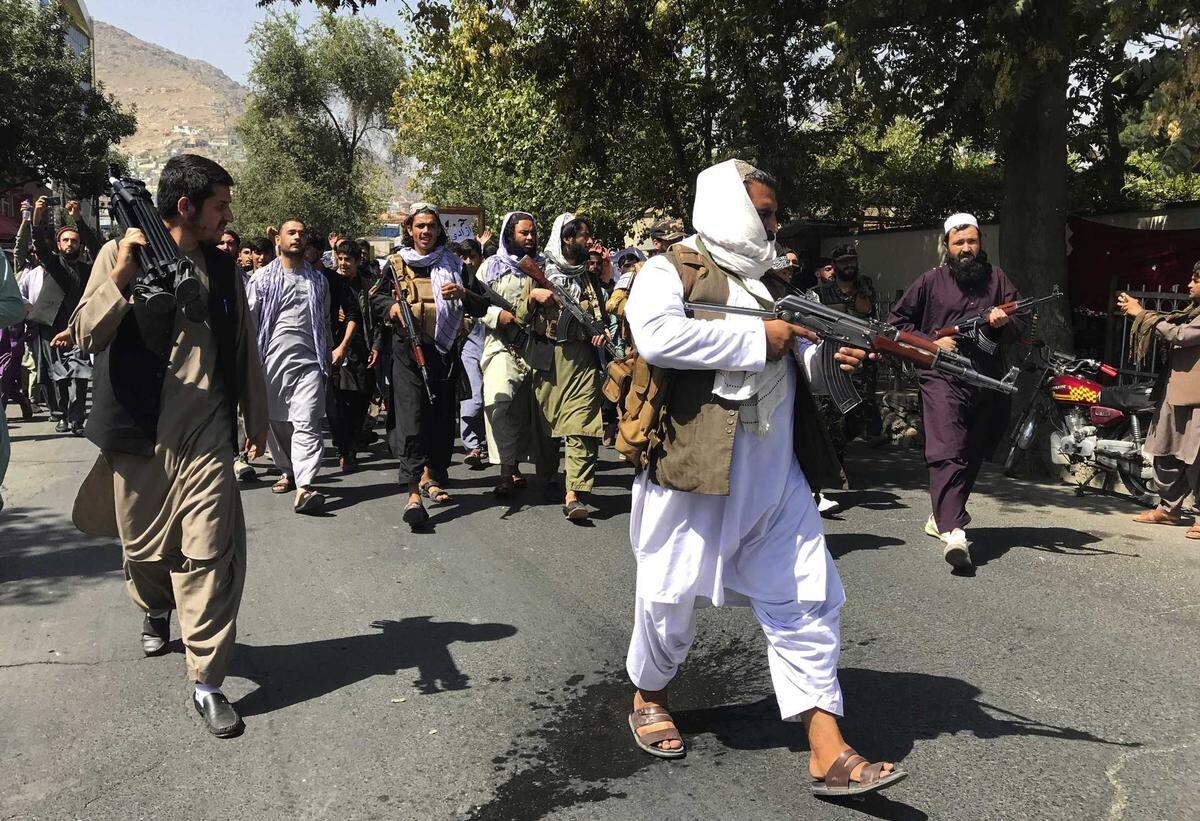 Taliban soldiers walk towards Afghans shouting slogans, during an anti-Pakistan demonstration, near the Pakistan embassy in Kabul, Afghanistan, Tuesday, Sept. 7, 2021. After the Taliban takeover, employees of the collapsed government, civil society activists and women are among the at-risk Afghans who have gone into hiding or are staying off the streets.