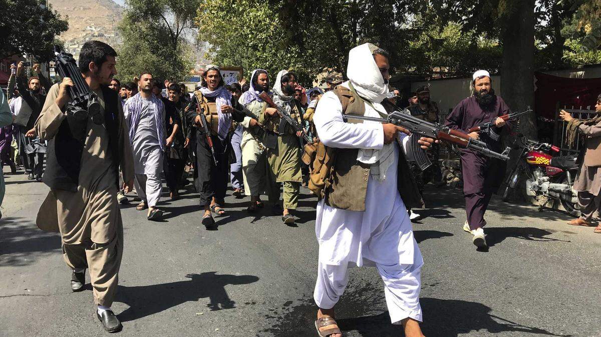 Taliban soldiers walk towards Afghans shouting slogans, during an anti-Pakistan demonstration, near the Pakistan embassy in Kabul, Afghanistan, Tuesday, Sept. 7, 2021. After the Taliban takeover, employees of the collapsed government, civil society activists and women are among the at-risk Afghans who have gone into hiding or are staying off the streets.