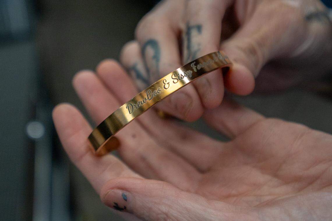 Erika Pringle holds a bracelet engraved with her brother Andrew Pringle’s name that reads “Drew-Boo & Sissy Forever and Always” in July at a salon where she works in Sacramento. She says having pictures and mementos nearby helps her focus on the good times with her brother rather than the traumatic memories of his death in the accident.