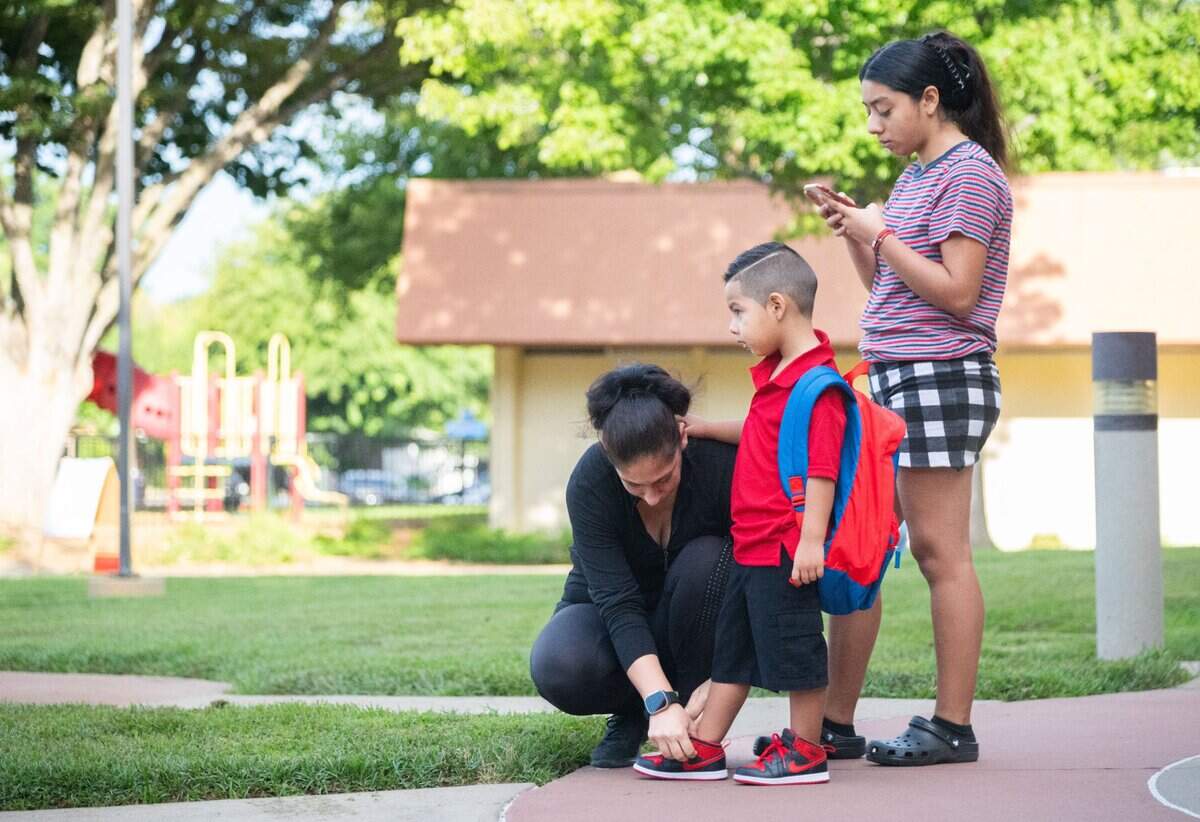 Josefina Coti, left, ties her son Jordan’s shoe while Amber Alvarado, left, looks at her phone on the first day of classes at Williamson Elementary School in Rancho Cordova on Thursday, Aug. 8, 2024. Josefina Coti said that while she is nervous for her son to start kindergarten, he is feeling excited.