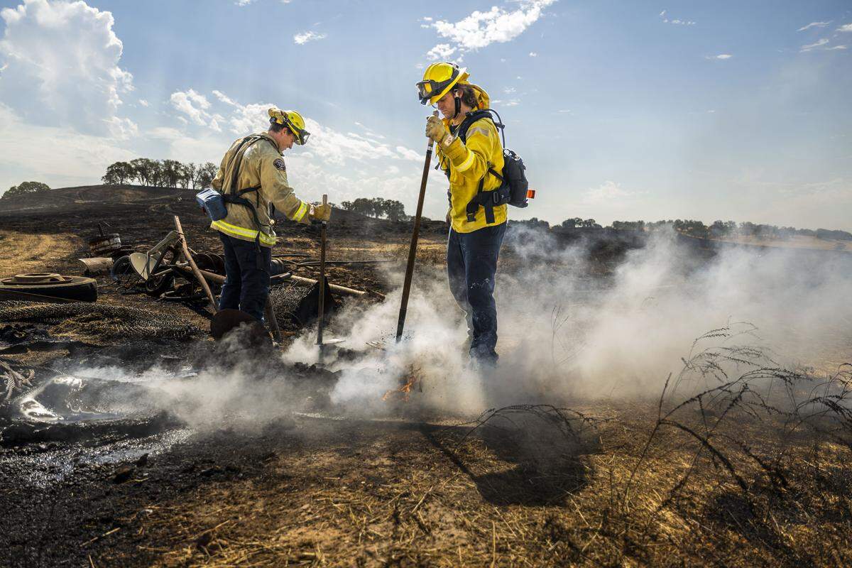Sacramento Metro firefighters Nick Wanner and Michael Monrean mop up a hot spot on Ione Road during the Brown Fire near Rancho Murrieta on Tuesday, Sept. 2, 2025.