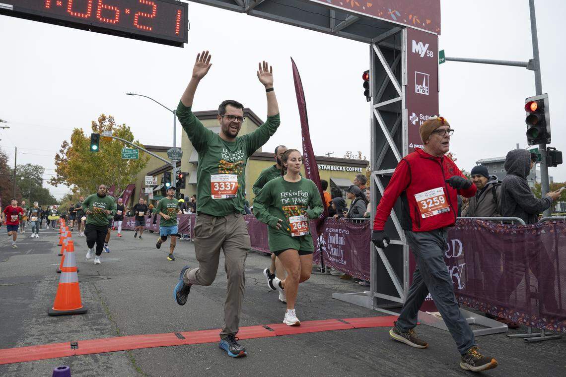 Runners cross the finish line of the 10k race during the Run to Feed the Hungry in Sacramento on Thursday, Nov. 27, 2025.