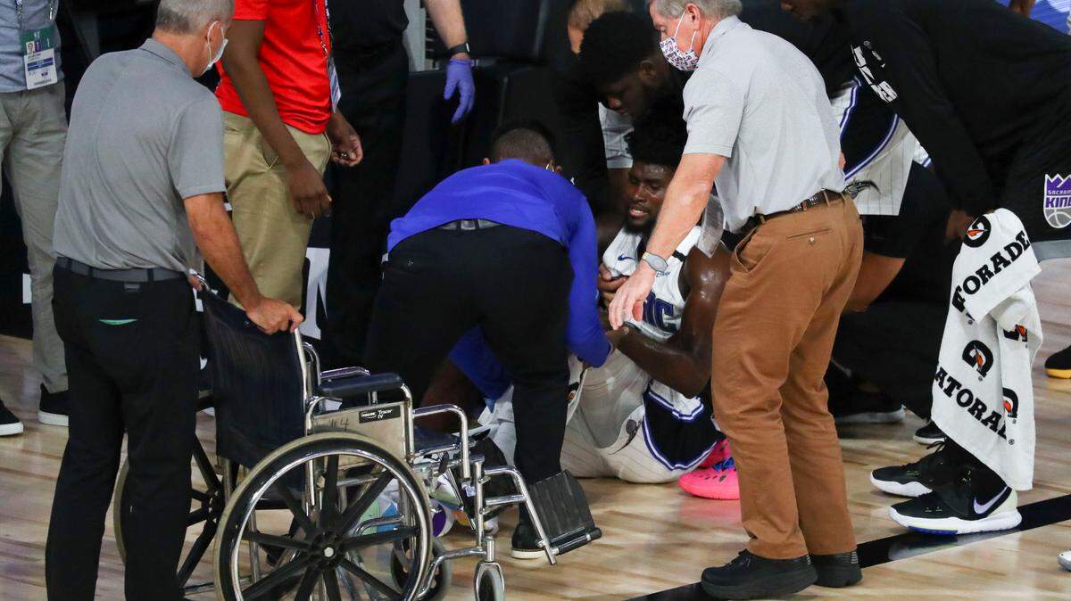 Sacramento Kings center Harry Giles III, right, and others check on Orlando Magic forward Jonathan Isaac (1) as he is helped into a wheelchair after he suffered an injury during the second half of their game on Sunday, Aug. 2, 2020, in Lake Buena Vista, Fla. (Kim Klement/Pool Photo via AP)