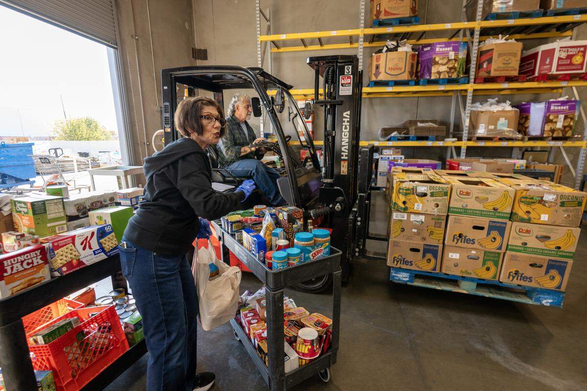 Terrie Erwin puts donations on a cart as forklift driver Michael Green brings in a fruit donation at the Elk Grove Food Bank on Saturday in Elk Grove. The food bank has experienced a significant increase in clients seeking assistance due to the pause in the SNAP program and the ongoing government shutdown.