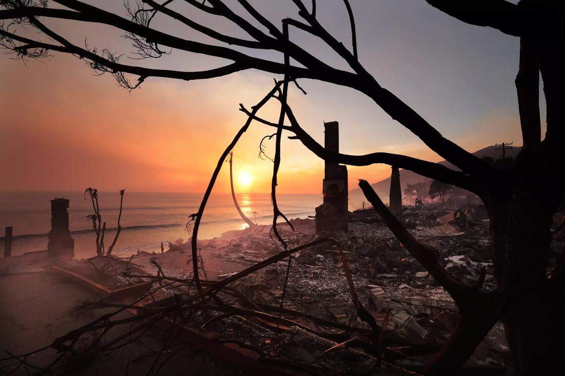The sun sets on Wednesday, Jan. 8, 2025, near burned beachfront homes. Nearly 20,000 acres – about 31 square miles – have burned in the Palisades fire.
