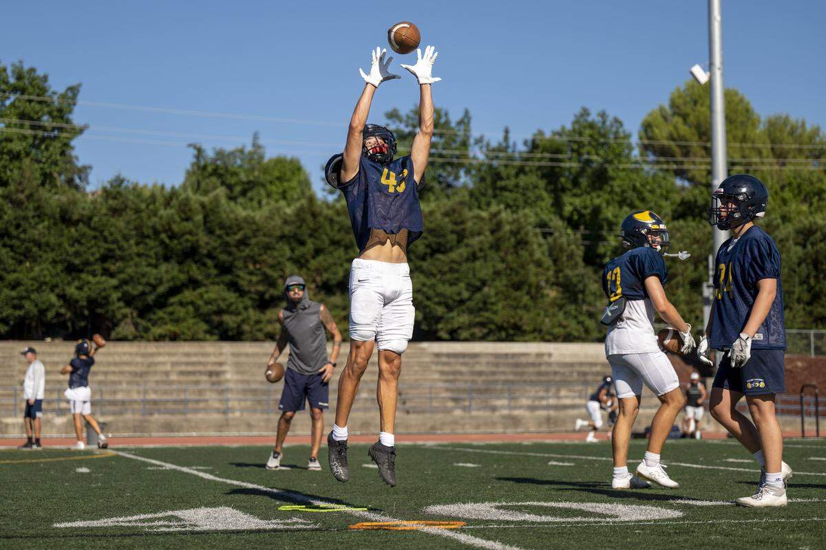 A receiver jumps to catch the ball during a football practice at Oak Ridge High School in El Dorado Hills on Tuesday, Aug. 5, 2025.