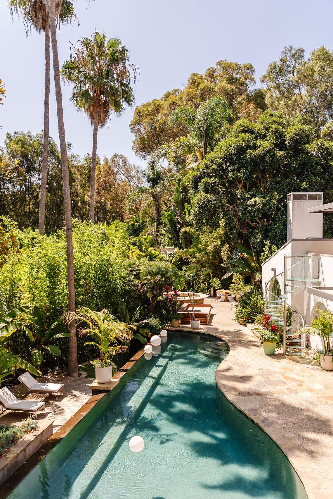 The park-like grounds boast a sparkling outdoor pool, hot tub, bocce ball court, outdoor kitchen, and lush gardens — blurring the boundaries between indoor comfort and natural beauty.
