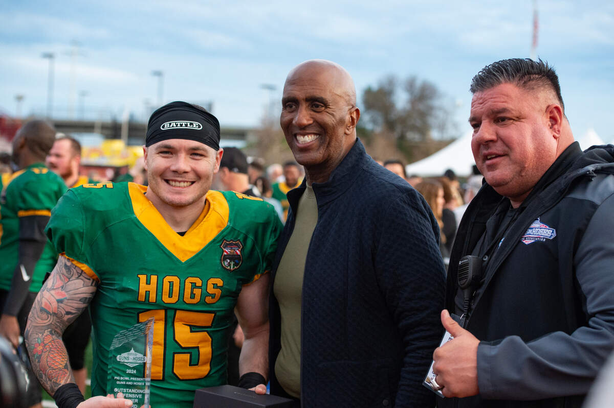 The Law Hogs’ Joshua Gurnaby holds one of the Pig Bowl MVP trophies as he stands with Sacramento Sheriff Jim Cooper, center, and game director Cary Trzcinski after the 50th anniversary game at Hughes Stadium in 2024.