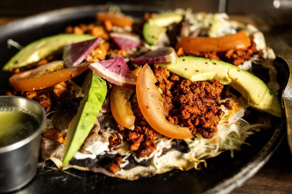 The tlayuda ($19) is a crisped tortilla served with chorizo, beef and al pastor at Oaxaca Coctelería and Mezcalería.