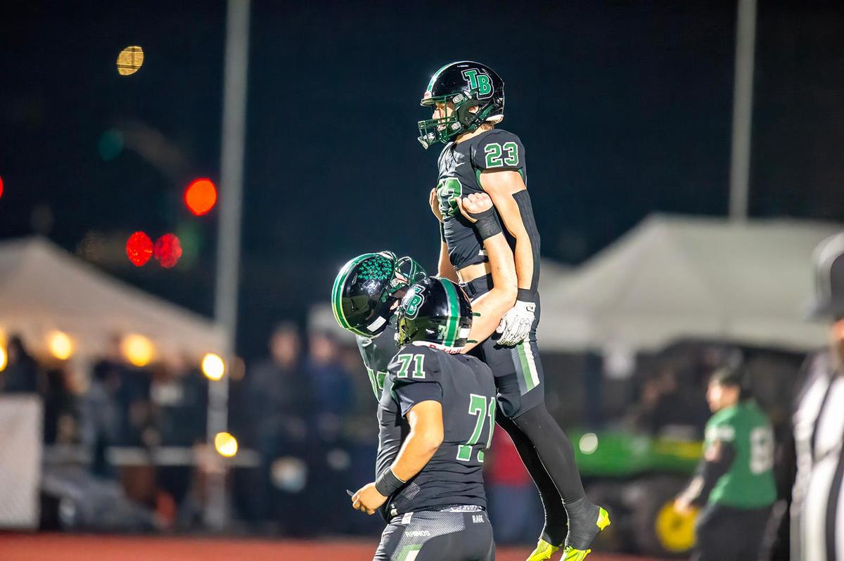 Twelve Bridges Raging Rhinos’ Caleb Amos (72) hoist Rhinos’ Braeden Ward (23) to the air following his 2-point conversion in the second quarter of the CIF Northern California Division 2-A championship game on Saturday, Dec. 7, 2024, in Lincoln.
