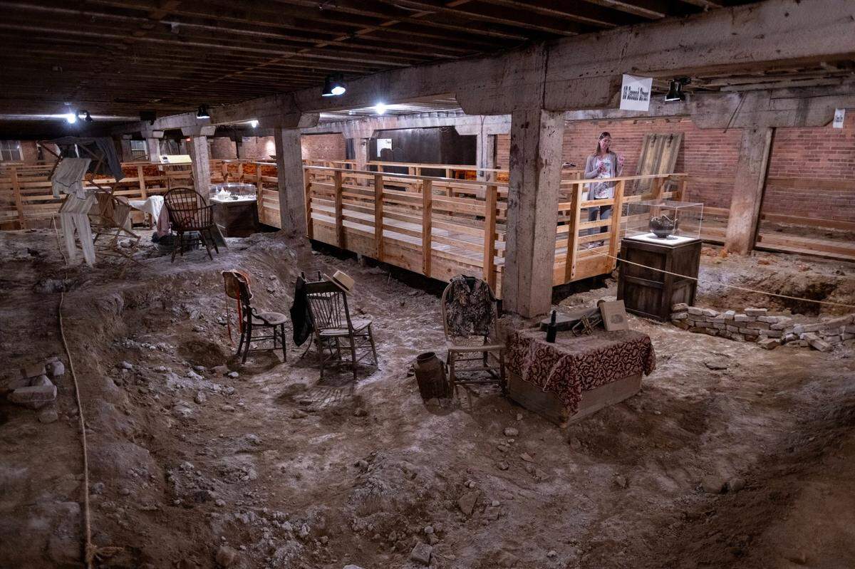 Aly Kowalski, experience manager for the Sacramento History Museum, stands near 1800s artifacts in the underground area Old Sacramento’s Hall, Luhrs & Company on Friday, Aug. 23, 2024.