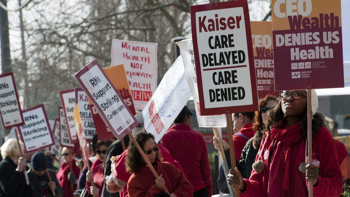 Gabrielle Soumah, right, holds two signs as she participates in a 2012 strike held by the National Union of Healthcare Workers and the California Nurses Association outside a Kaiser Permanente hospital in Sacramento. This year, the nurses union settled their contract days before a planned strike.
