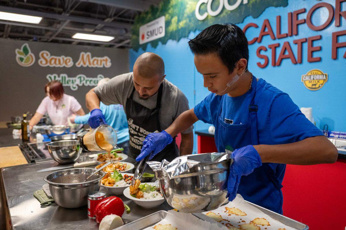 Roberto Alvarado, 12, adds shrimp to his entry while his father Roberto Alvarado Sr. pours chipotle sauce during the California Junior Chef Cooking Challenge at the California State Fair on Tuesday, July 22, 2025, in Sacramento.