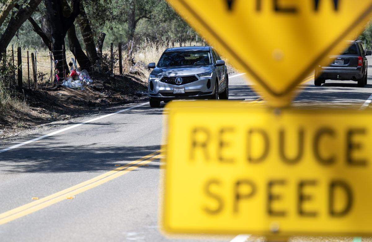 A vehicle drives past a memorial to high school students Ariyonna Orozco, 16, and Piper Conkling, 14, on Scott Road near Rancho Murieta on Tuesday. The teens died after their vehicle crashed into a tree and caught fire days before. Investigators said speed was a factor in the crash.